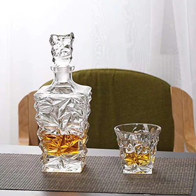 Crystal whiskey decanter and matching glass with amber liquid on a table