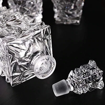 Crystal whiskey decanter with faceted stopper on a black surface, barware accessory