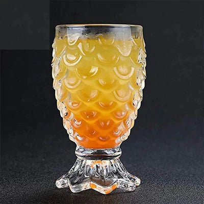 Textured pineapple-pattern glass goblet filled with orange and yellow cocktail on dark background