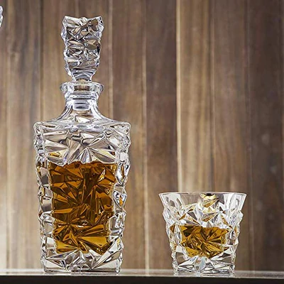Crystal whiskey decanter and glass set with amber liquor on wooden surface