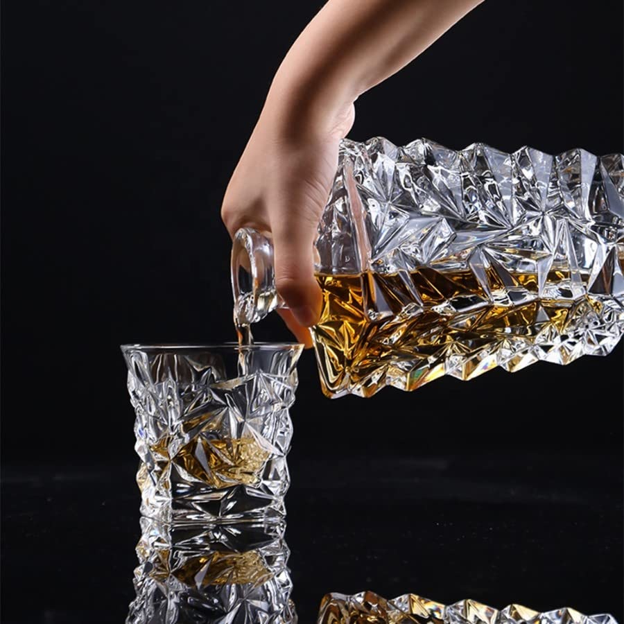 Hand pouring whiskey from a crystal decanter into a matching whiskey glass