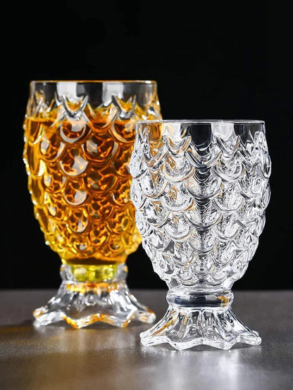 Two textured whiskey glasses with unique scalloped design on a table, one filled with amber liquid.