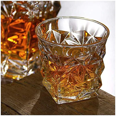 Faceted crystal whiskey glass filled with amber liquor on a rustic wooden surface
