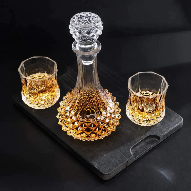 Diamond cut whiskey decanter and two matching glasses with whiskey on a black tray