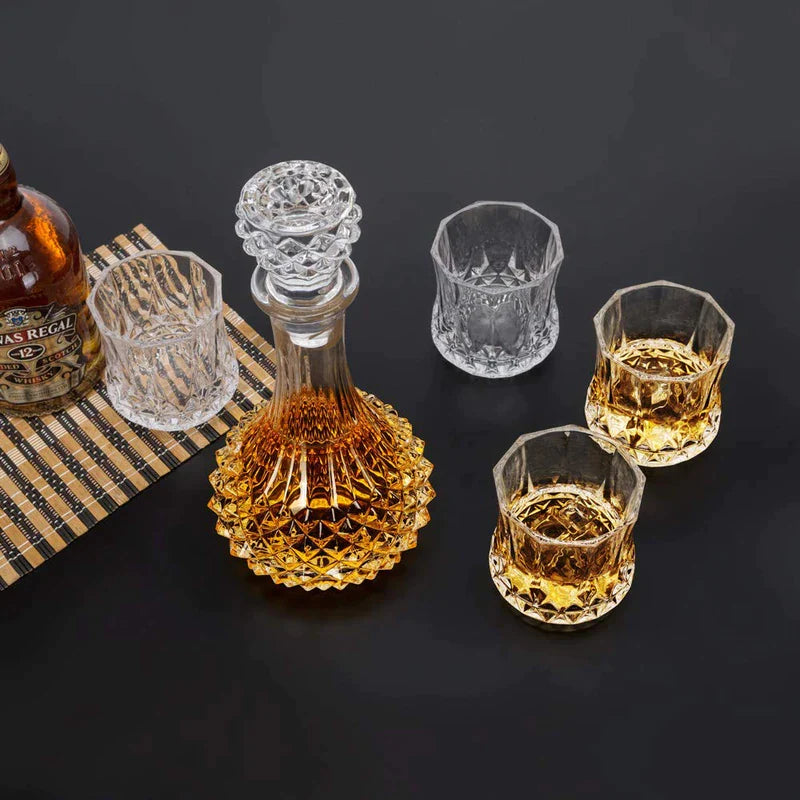 Crystal whiskey decanter with matching whiskey glasses on black tabletop, barware set