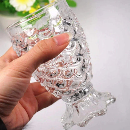 Hand holding textured glass fish-shaped goblet against a light background