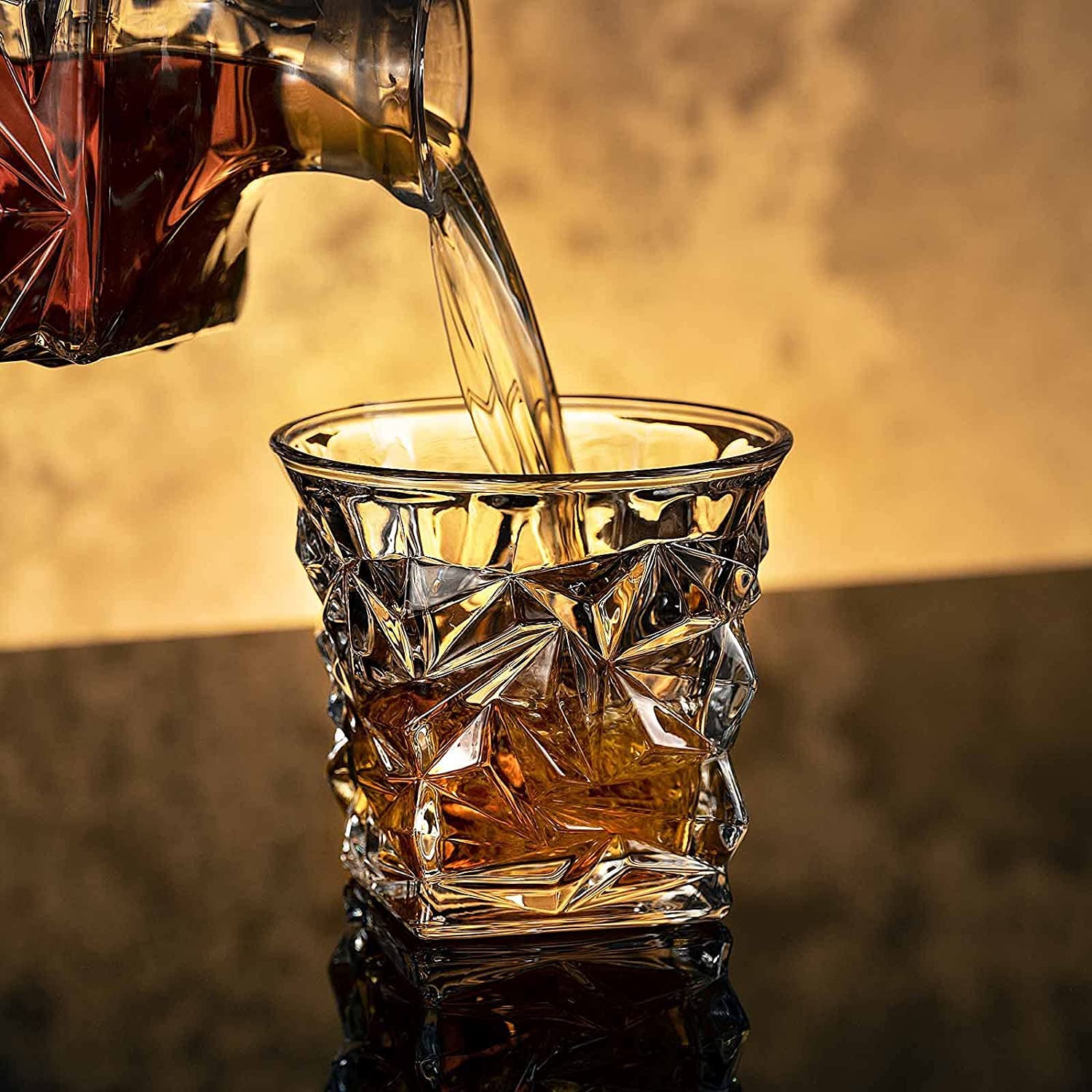 Whiskey being poured into a faceted crystal whiskey glass on a reflective bar surface