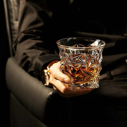 Hand holding a crystal whiskey glass with amber liquor in an elegant bar setting