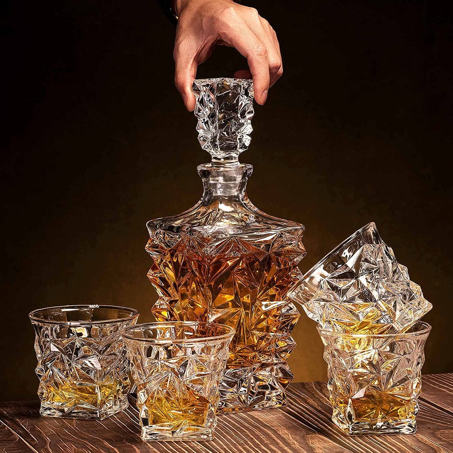 Crystal whiskey decanter set with angular glasses, filled with whiskey on wooden table