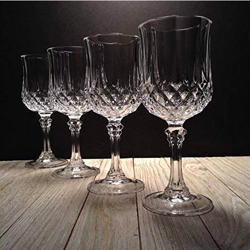 Set of four crystal wine goblets with elegant cut glass pattern on wooden surface