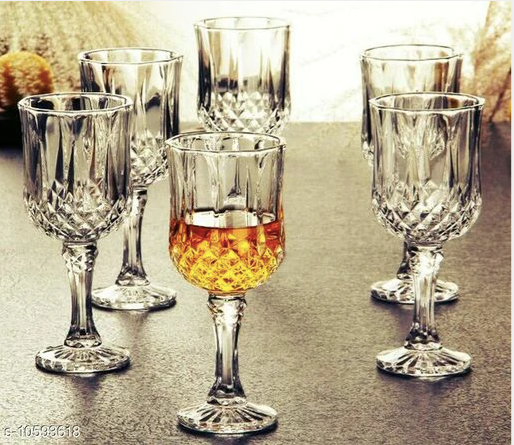 Set of six crystal whiskey glasses, one filled with amber liquid, on a tabletop