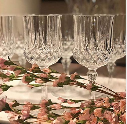 Elegant crystal wine glasses with floral pattern details, arranged behind pink blossoms