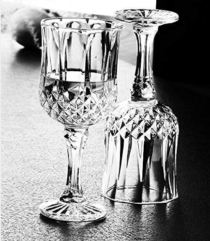 Crystal wine goblets with etched patterns, one upright and one upside down on tabletop