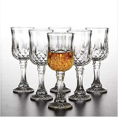 Set of six crystal whiskey glasses, one filled with amber liquid, on a reflective surface
