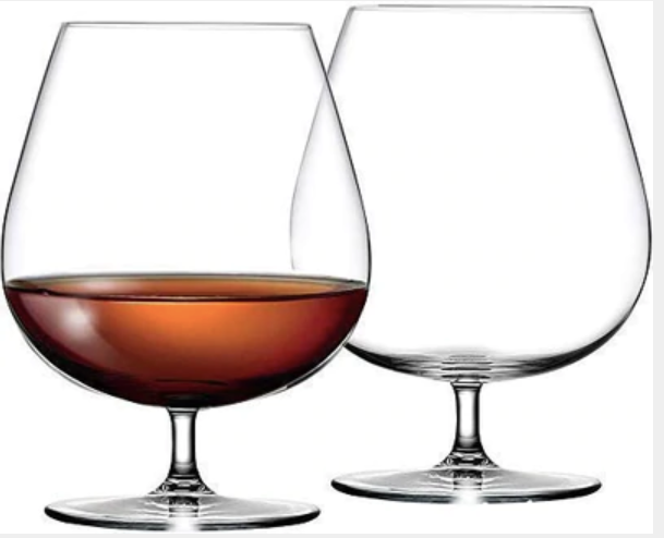 Set of two clear brandy snifter glasses, one filled with amber liquor, on white background
