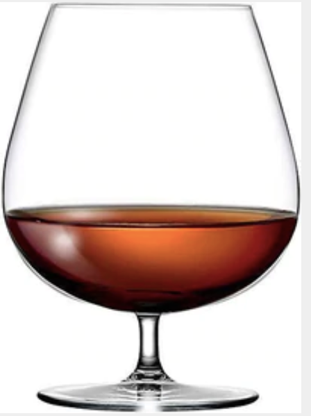 Clear brandy snifter glass filled with amber whiskey on a white background