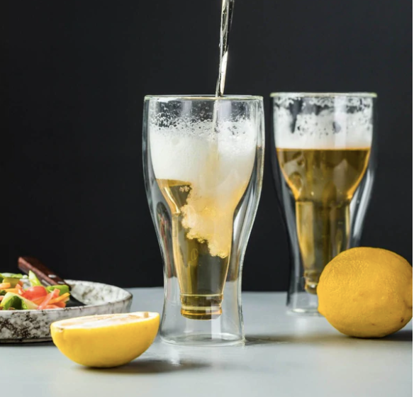 Double-walled beer glasses with beer, lemons, and salad on a modern bar setup